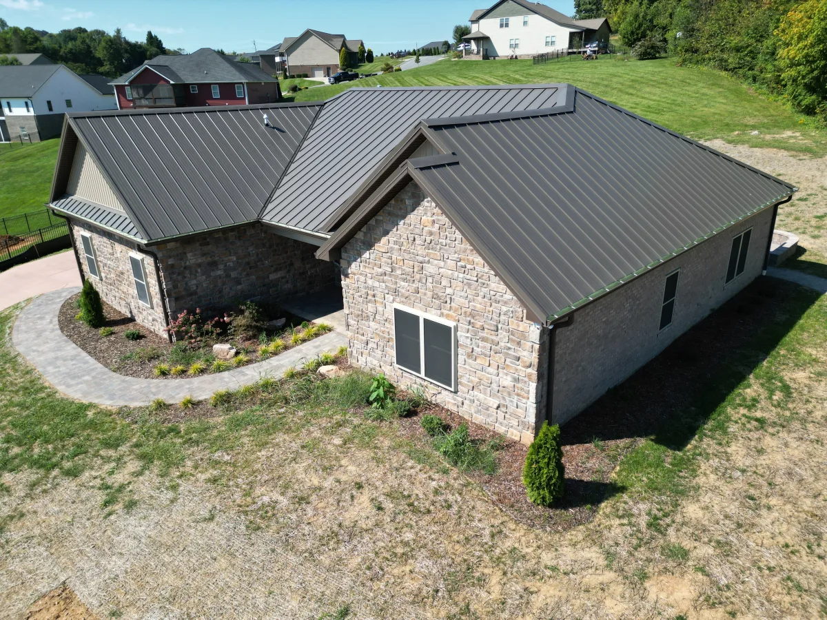 Antique bronze standing-seam metal roof on a stone-veneer ranch — completed by Palisade Roofing.