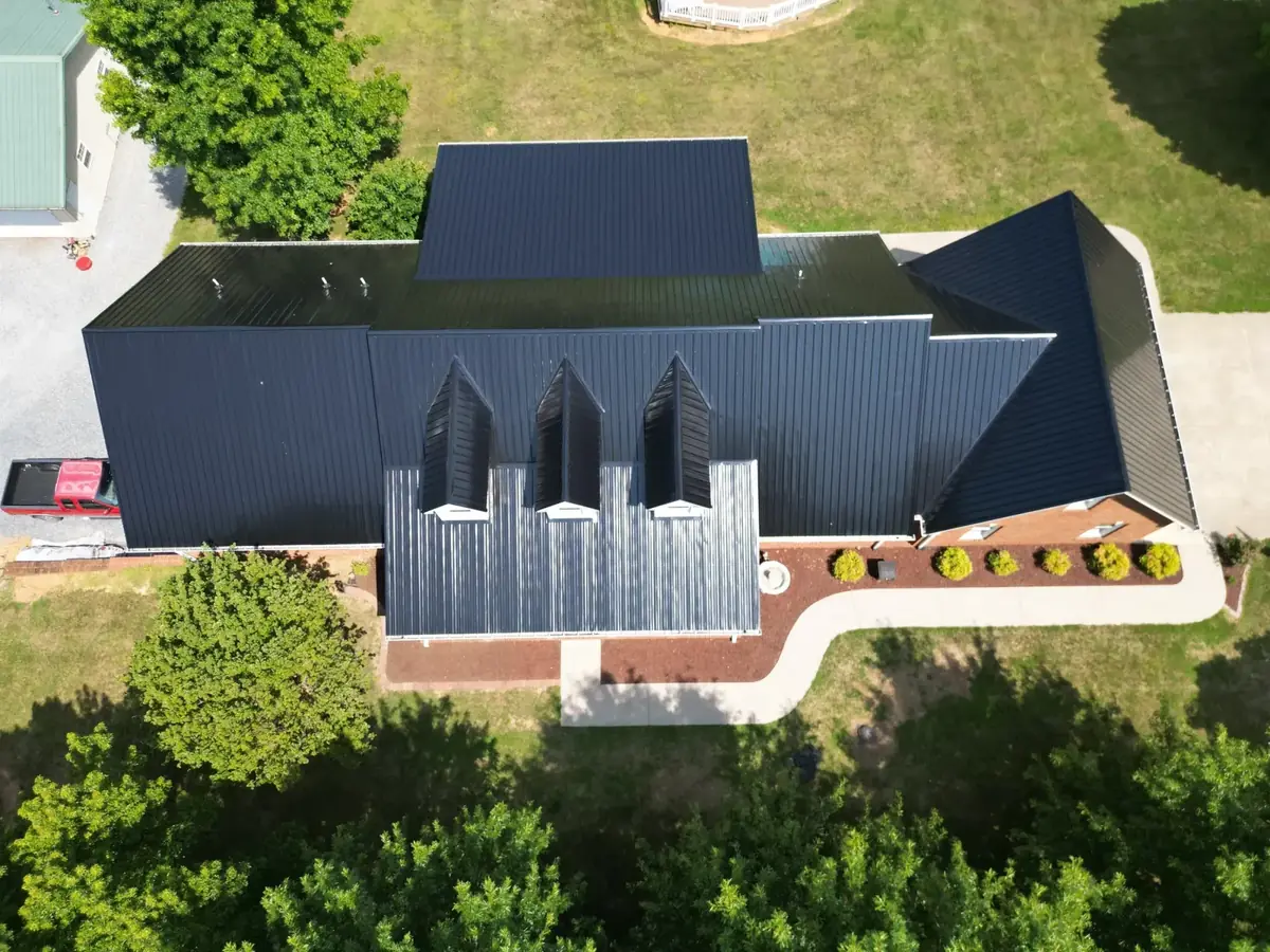 Black standing-seam metal roof on a long Tri-Cities home with multiple peaks — a Palisade Roofing installation.