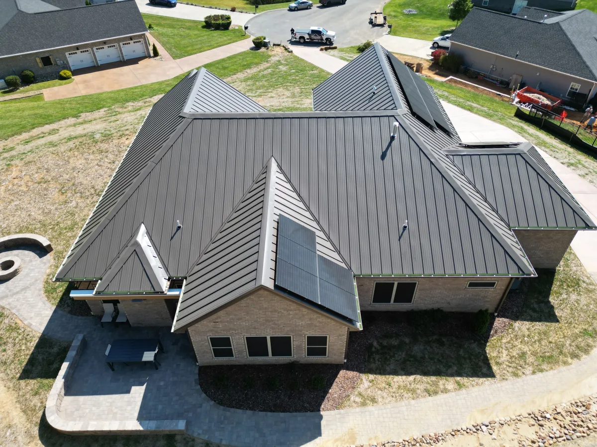 Burnished bronze standing-seam metal roof on a brick ranch with a small solar array — completed by Palisade Roofing in the Tri-Cities.