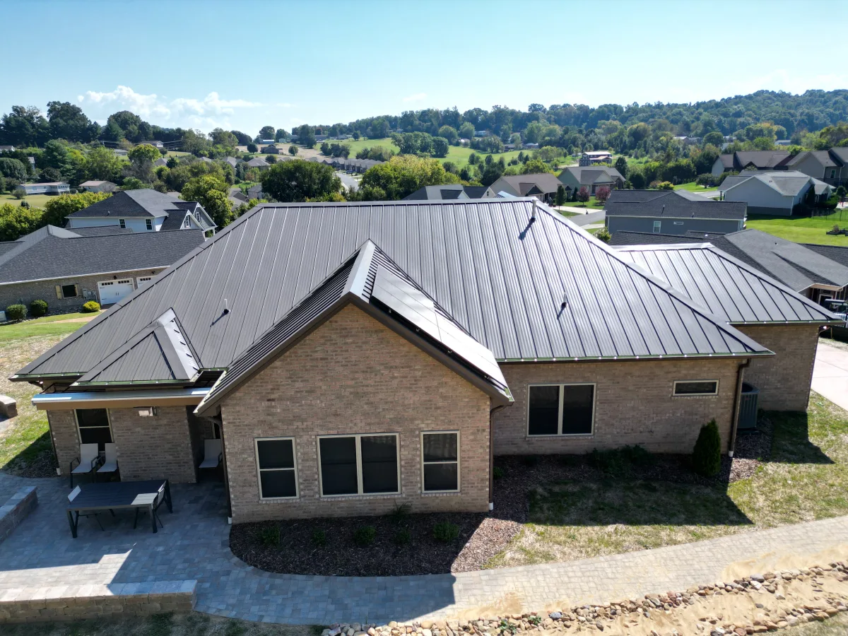 Matte black standing-seam metal roof on a brick ranch with a valley view — a Palisade Roofing install in East Tennessee.