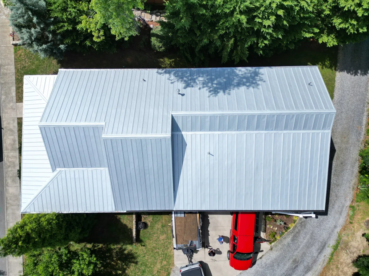 Bright silver standing-seam metal roof seen from above on a Tri-Cities farmhouse — completed by Palisade Roofing.