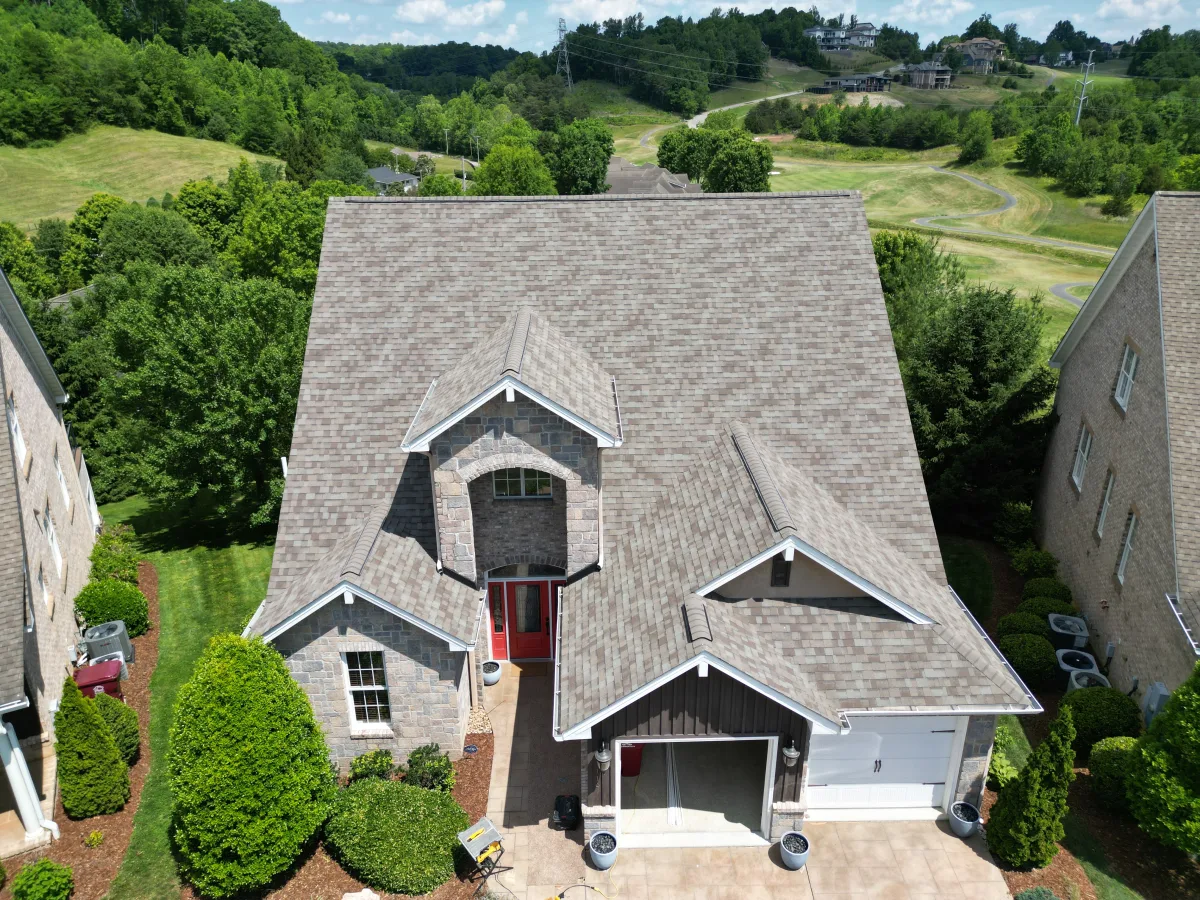Weathered Wood architectural shingles on a gray-brick home with a red front door and a gabled roofline — completed by Palisade Roofing in the Tri-Cities.