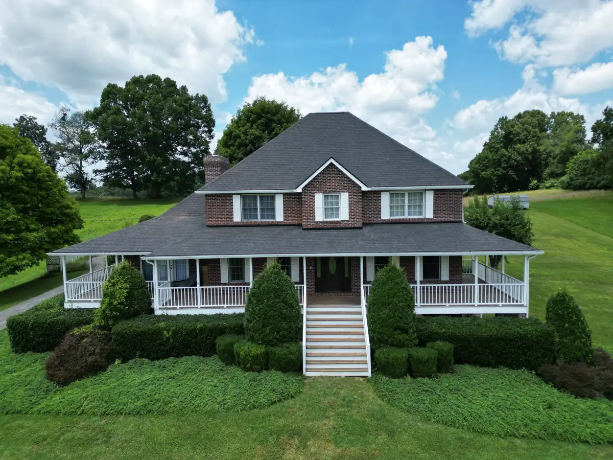 Asphalt shingle roof on a brick farmhouse with a wraparound porch — completed by Palisade Roofing in East Tennessee.